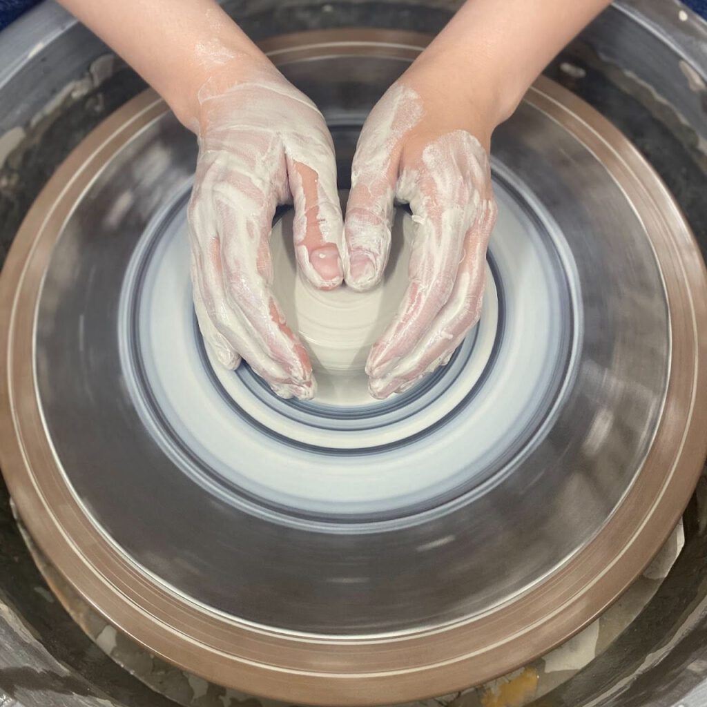 Gently forming clay on a wheel with two symmetrical hands