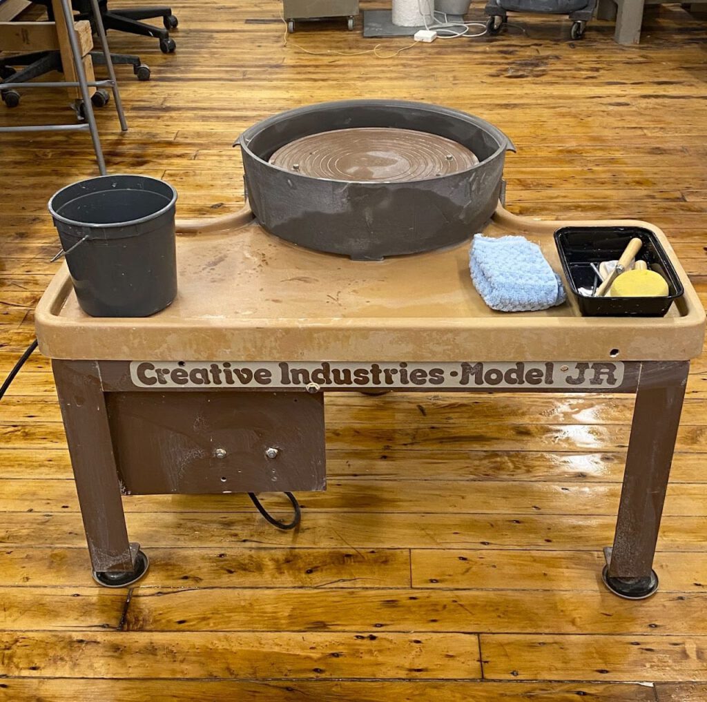 A pottery wheel and tools on a wooden table